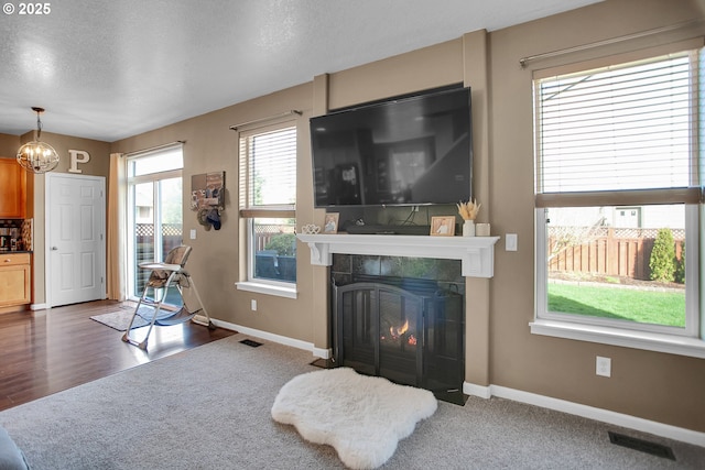 living room featuring baseboards, a tile fireplace, visible vents, and a notable chandelier