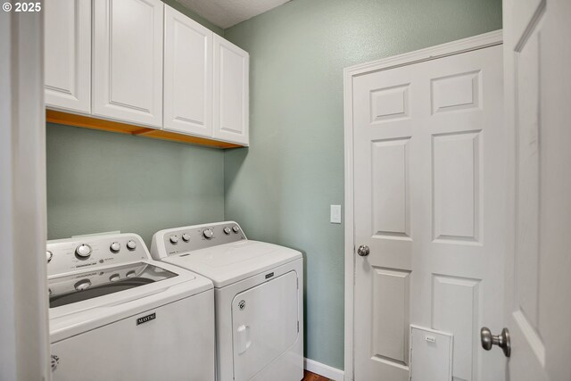 washroom featuring baseboards, cabinet space, and washing machine and clothes dryer