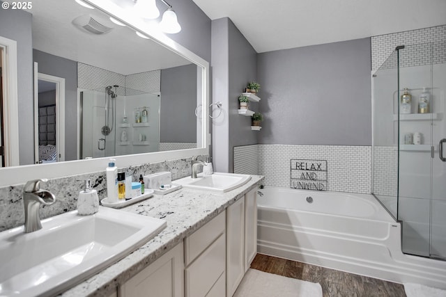 bathroom featuring a stall shower, a garden tub, a sink, and wood finished floors