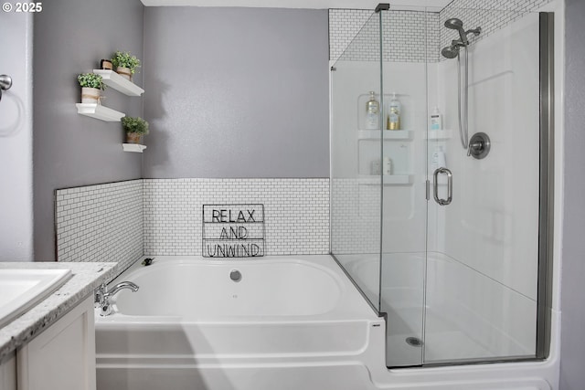 bathroom featuring a stall shower, a garden tub, and vanity