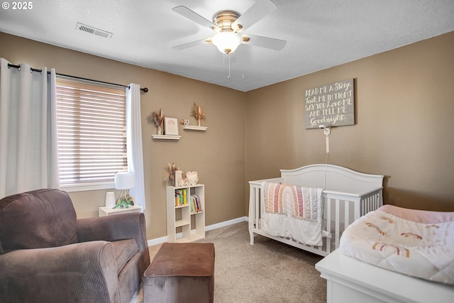 bedroom featuring ceiling fan, carpet flooring, visible vents, baseboards, and a nursery area