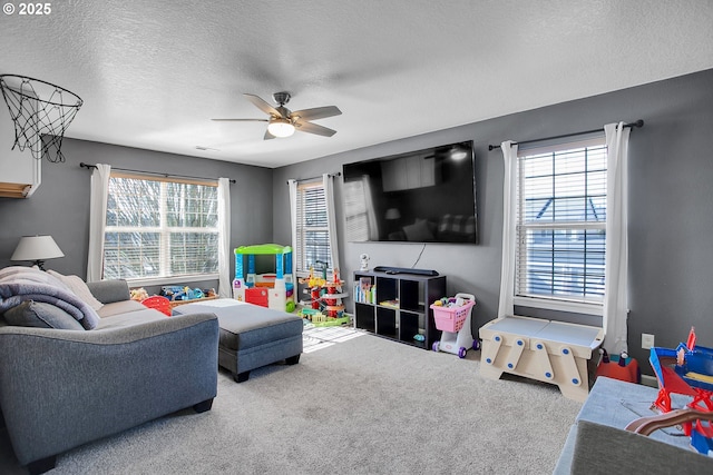 living room with ceiling fan, a textured ceiling, carpet, and a wealth of natural light