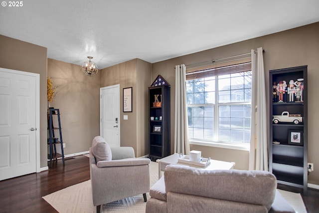 living room featuring a chandelier, dark wood-style flooring, and baseboards