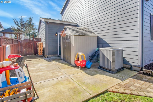 view of patio / terrace with central AC unit, a gate, fence, a shed, and an outdoor structure