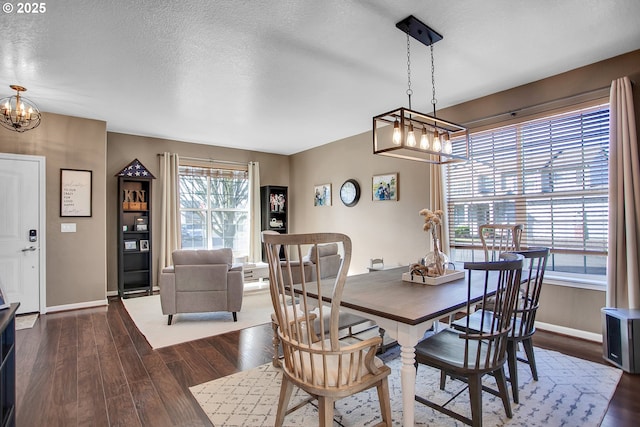 dining room with a notable chandelier, dark wood finished floors, a textured ceiling, and baseboards