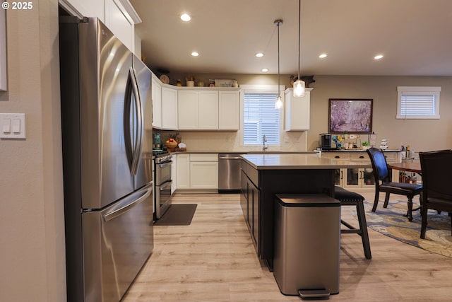 kitchen with white cabinetry, light wood-type flooring, appliances with stainless steel finishes, and a breakfast bar