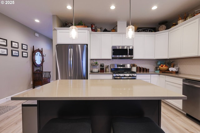 kitchen with decorative backsplash, light wood finished floors, and stainless steel appliances