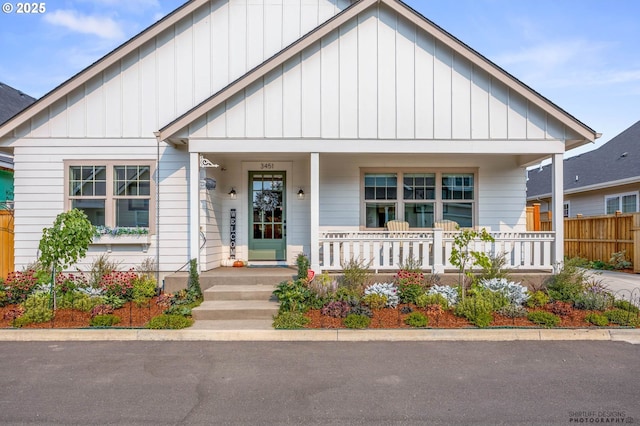 modern inspired farmhouse featuring a porch, board and batten siding, and fence