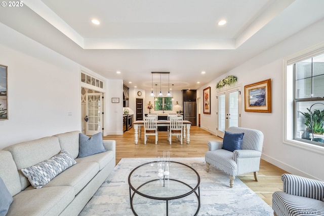 living room with plenty of natural light, french doors, and light wood-style flooring