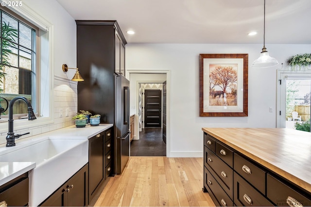 kitchen featuring light wood-type flooring, recessed lighting, a sink, wood counters, and decorative light fixtures