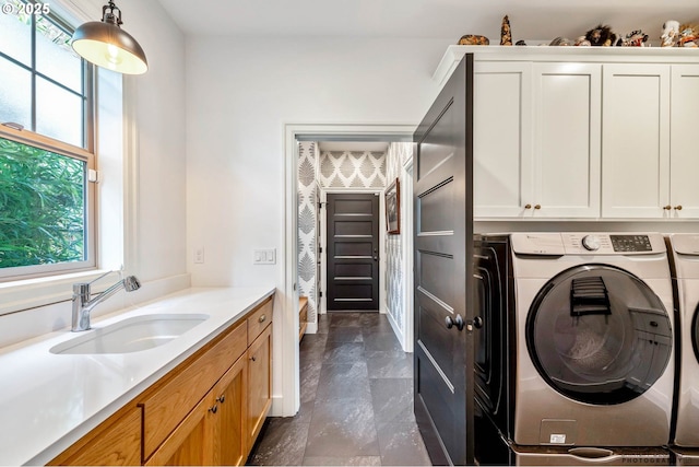 clothes washing area with washer and clothes dryer, a sink, and cabinet space