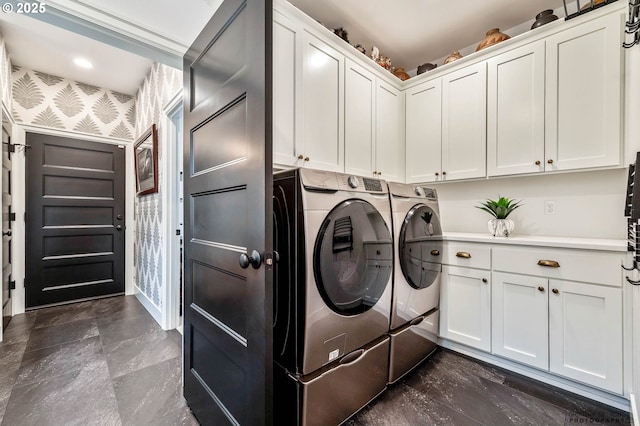 laundry area featuring washing machine and dryer, wallpapered walls, and cabinet space
