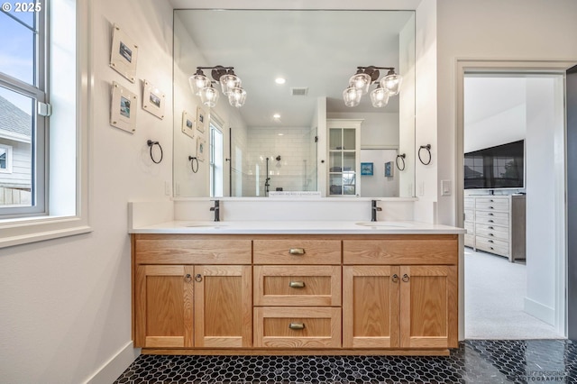 bathroom with a sink, baseboards, a shower stall, and double vanity