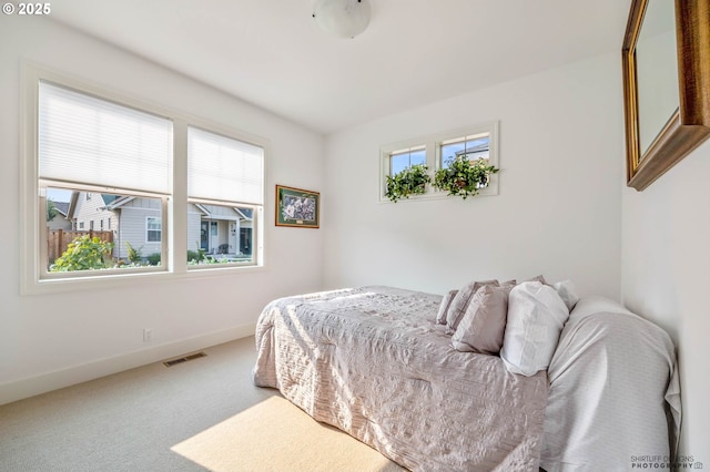 bedroom featuring carpet floors, baseboards, visible vents, and multiple windows