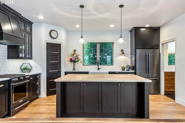 kitchen featuring a sink, premium range hood, stainless steel appliances, backsplash, and a kitchen island