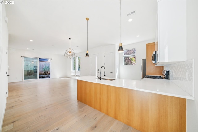2585 SE 13th Ave, Portland, OR 97202 - kitchen with a peninsula, light wood-style flooring, a sink, stainless steel microwave, and gas range oven