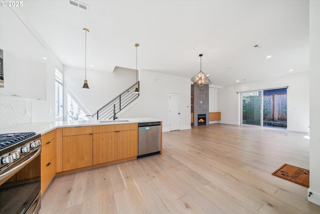 2585 SE 13th Ave, Portland, OR 97202 - kitchen featuring pendant lighting, light wood finished floors, light countertops, appliances with stainless steel finishes, and visible vents