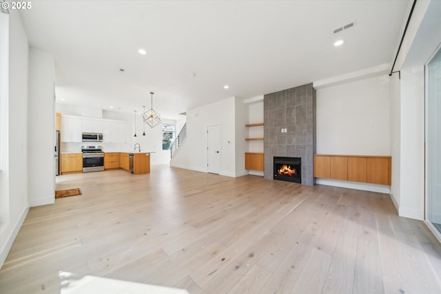 2585 SE 13th Ave, Portland, OR 97202 - unfurnished living room featuring baseboards, visible vents, recessed lighting, light wood-style floors, and a tile fireplace