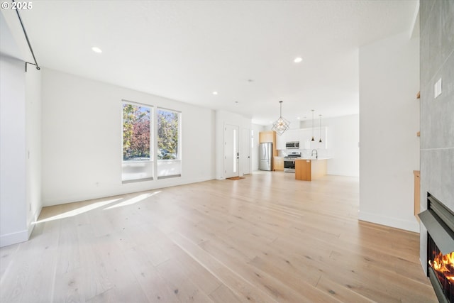 2585 SE 13th Ave, Portland, OR 97202 - unfurnished living room featuring light wood finished floors, baseboards, a large fireplace, and recessed lighting