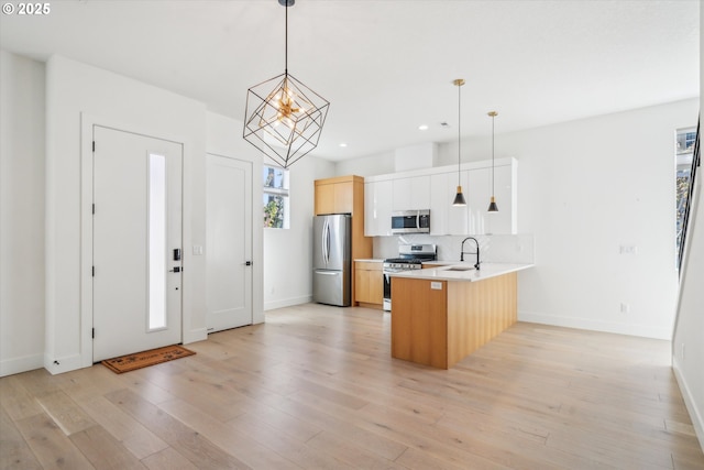 2585 SE 13th Ave, Portland, OR 97202 - kitchen featuring light countertops, backsplash, a peninsula, light wood-style flooring, and appliances with stainless steel finishes