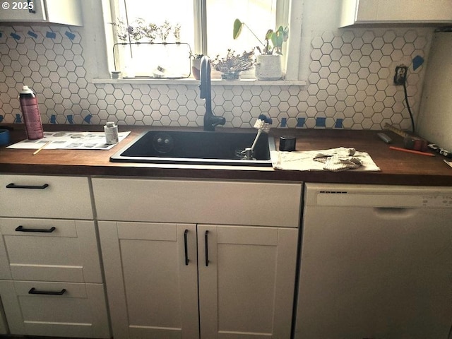 kitchen with butcher block countertops, white cabinets, sink, and white dishwasher