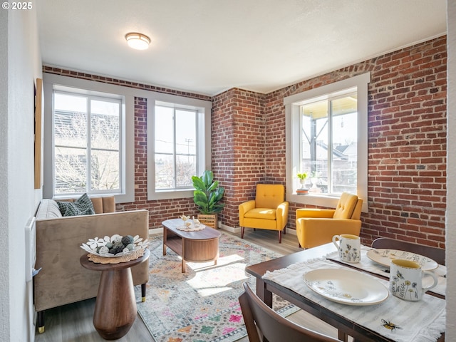living area featuring brick wall and wood finished floors