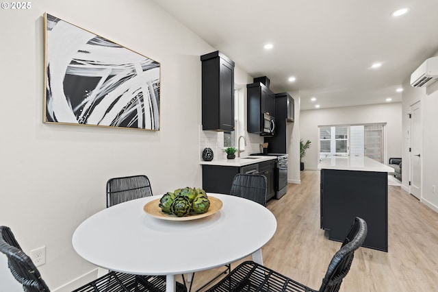 dining room with a wall mounted air conditioner, light wood-type flooring, and sink