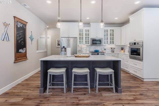 kitchen with stainless steel appliances, a center island, a kitchen bar, and tasteful backsplash