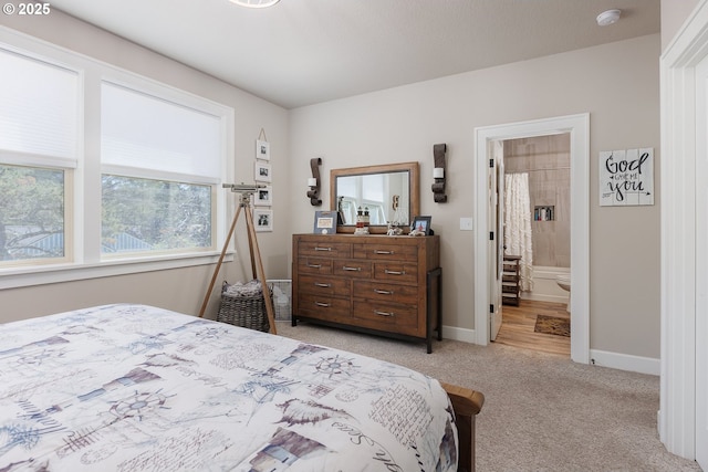 bedroom featuring ensuite bath, baseboards, and light colored carpet