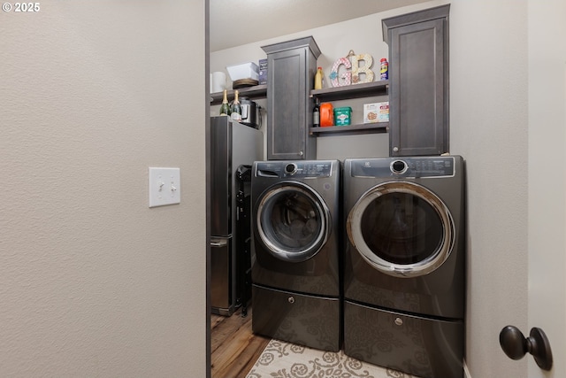 washroom featuring light wood-type flooring, cabinet space, and washing machine and clothes dryer