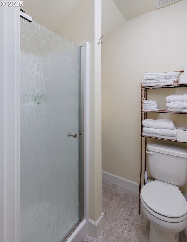 bathroom featuring visible vents, baseboards, toilet, lofted ceiling, and a shower stall