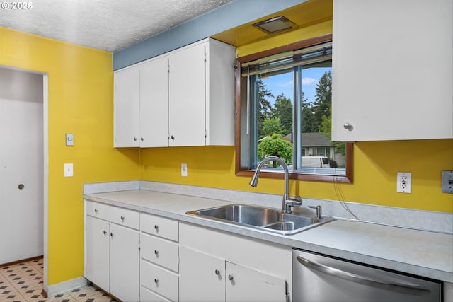 kitchen featuring stainless steel dishwasher, a sink, light countertops, white cabinets, and a textured ceiling