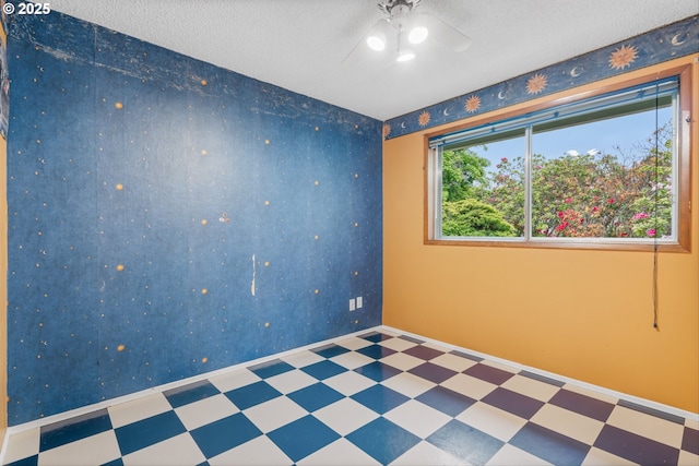 empty room featuring tile patterned floors, ceiling fan, and a textured ceiling