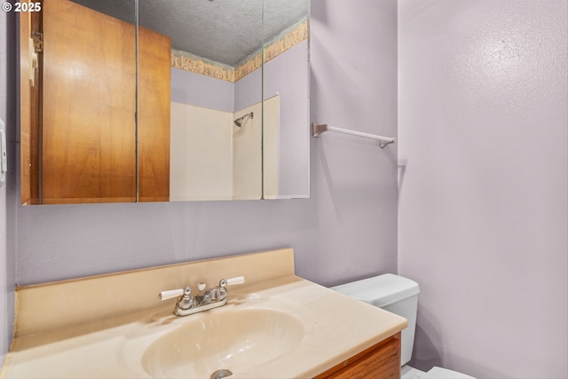 bathroom with toilet, vanity, and a textured ceiling