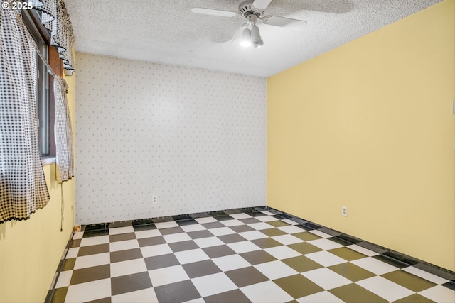 spare room with tile patterned floors, ceiling fan, a textured ceiling, wallpapered walls, and baseboards