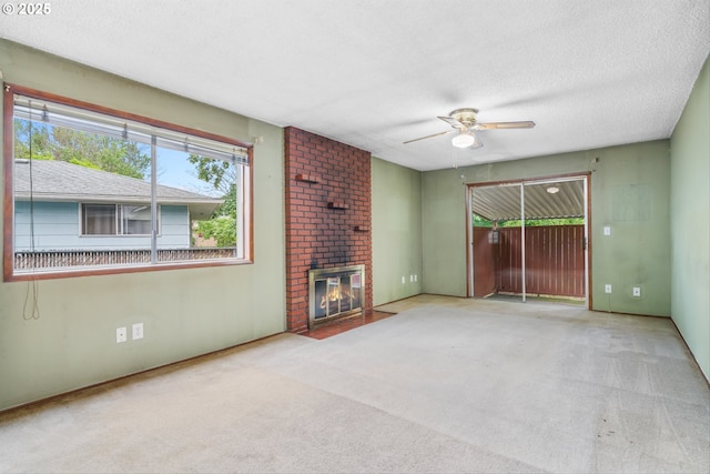 unfurnished living room with carpet, a ceiling fan, a fireplace, and a textured ceiling