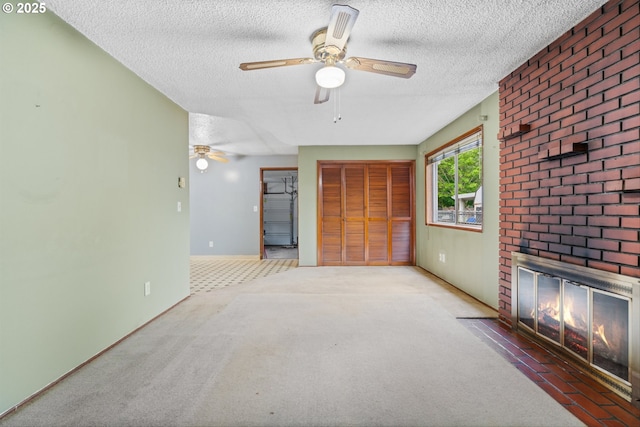 unfurnished living room with a textured ceiling, a ceiling fan, carpet flooring, a fireplace, and baseboards