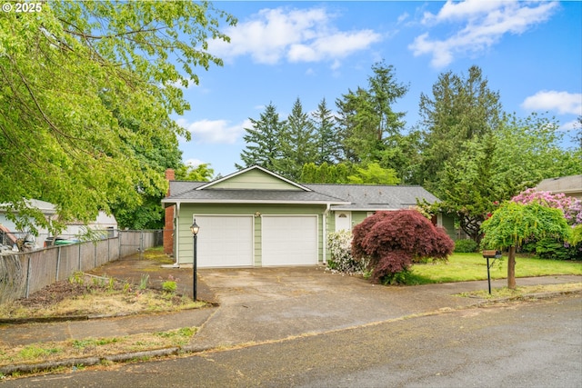 view of front of property featuring an attached garage, fence, concrete driveway, and a chimney