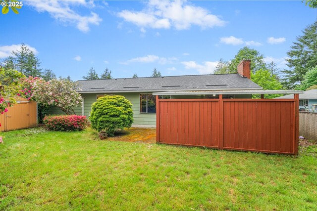 rear view of property featuring a shed, an outbuilding, a chimney, and roof with shingles