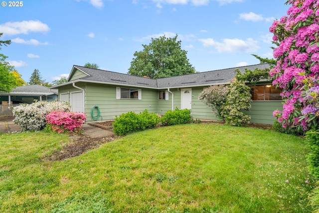 rear view of house featuring an attached garage and a yard