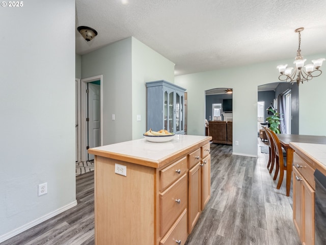 35530 Edies Way, Saint Helens, OR 97051 - kitchen featuring arched walkways, wood finished floors, a kitchen island, a textured ceiling, and a chandelier