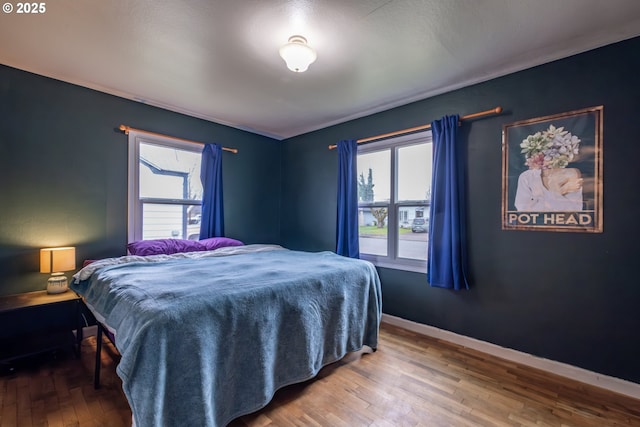 bedroom featuring baseboards, multiple windows, and wood finished floors