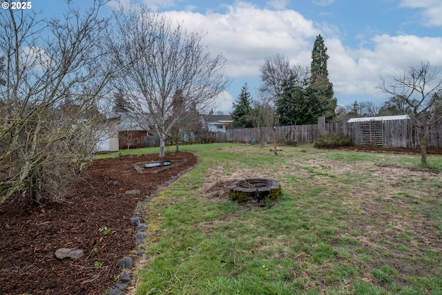 view of yard featuring an outbuilding, a fire pit, and fence