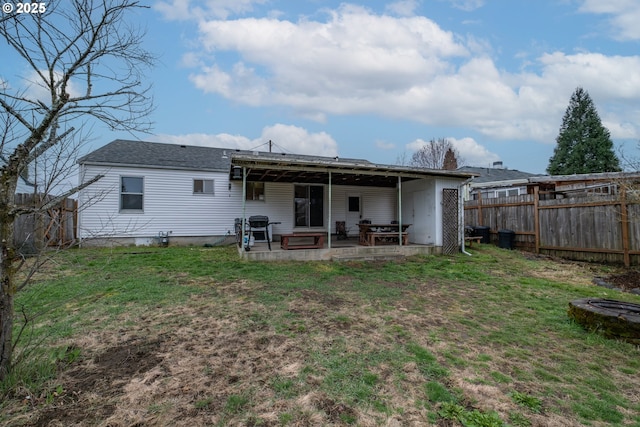 rear view of property featuring a yard, a patio area, and a fenced backyard