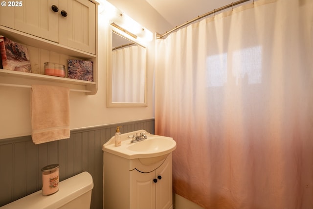 bathroom featuring a wainscoted wall, toilet, and vanity