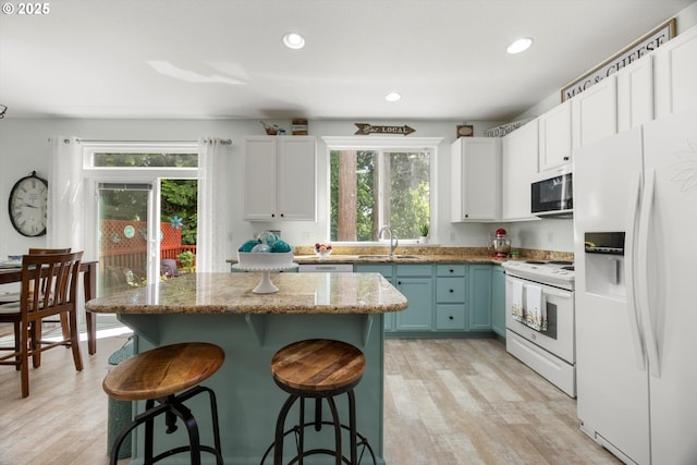 19774 SW Ashcroft Ln, Beaverton, OR 97003 - kitchen featuring white appliances, healthy amount of natural light, a sink, a kitchen bar, and recessed lighting