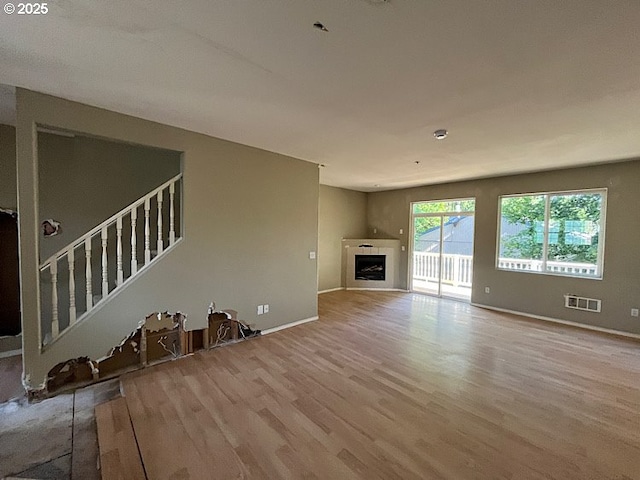 19903 SW Poplarwood Pl, Tualatin, OR 97062 - unfurnished living room featuring wood finished floors, a fireplace, and stairway