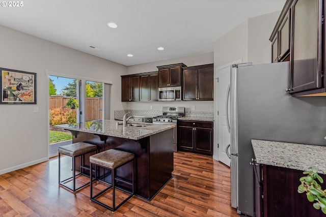 2908 S White Salmon Dr, Ridgefield, WA 98642 - kitchen featuring stainless steel appliances, dark wood finished floors, recessed lighting, light stone counters, and a kitchen bar