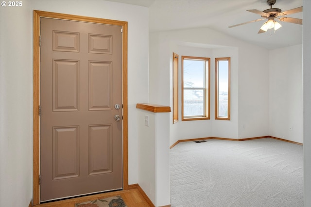 carpeted entryway with ceiling fan and lofted ceiling