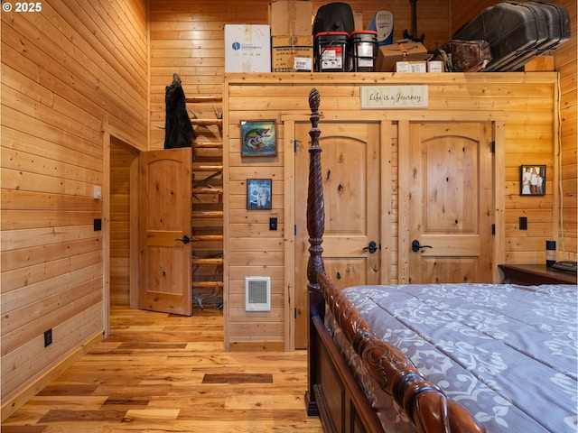 bedroom featuring light wood finished floors and wooden walls